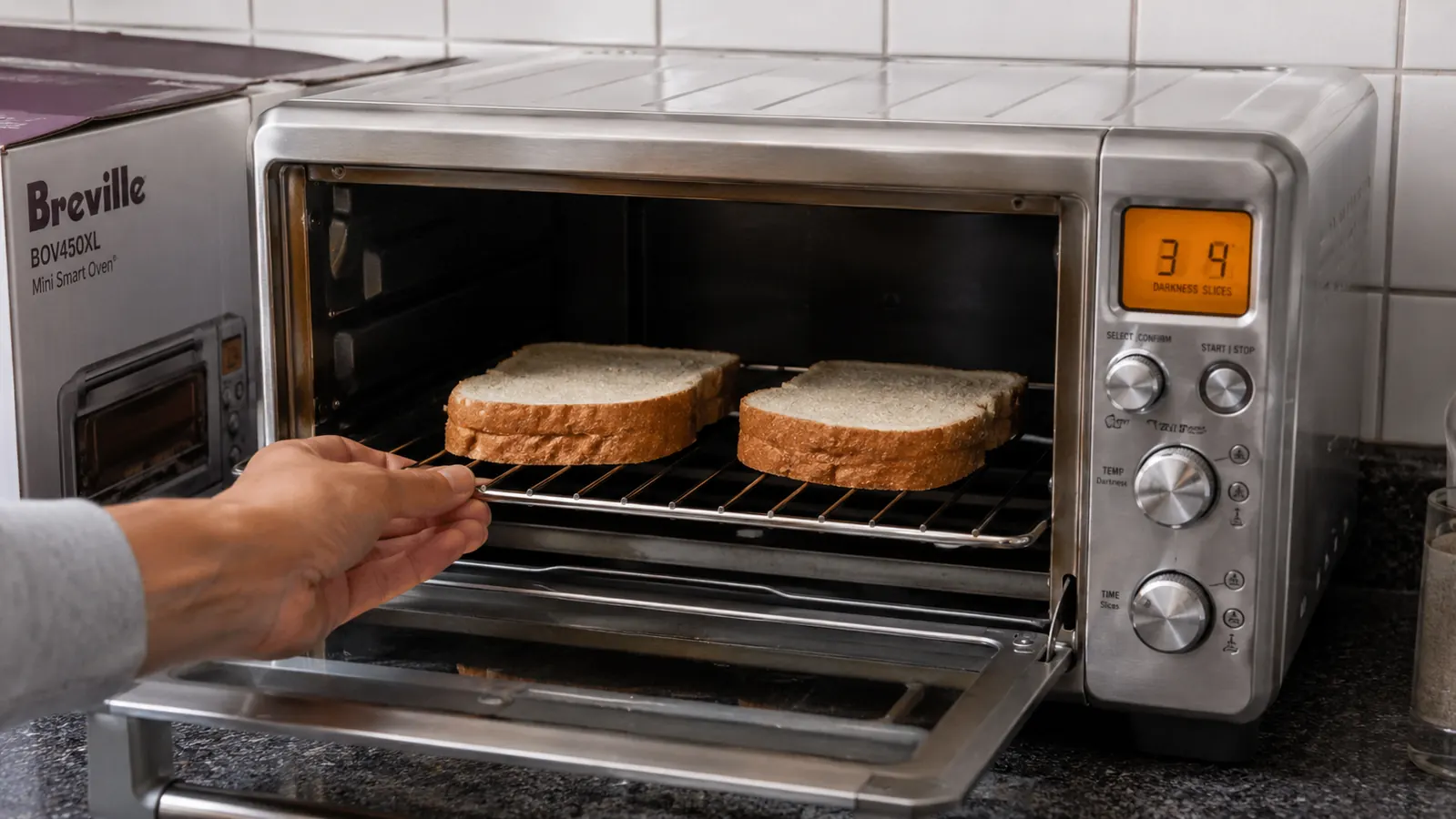 Breville BOV450XL with door open showing toast slots and interior rack on a brushed stainless surface
