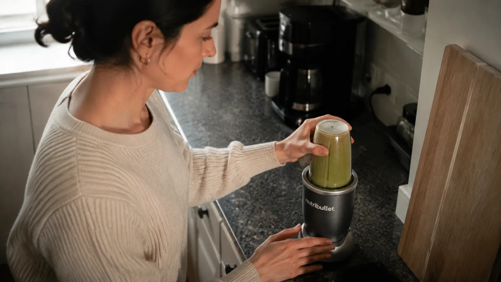 NutriBullet 600 cup sitting on a narrow apartment countertop beside a coffee maker, showing how little space it takes
